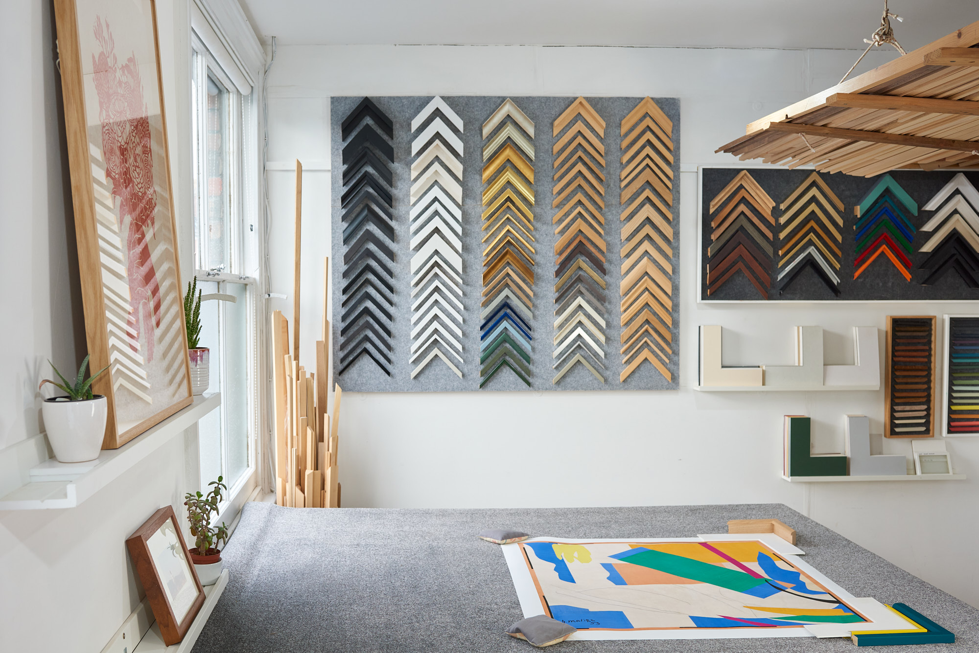 photograph of workshop scene with frame chevrons on back wall and grey carpeted bench